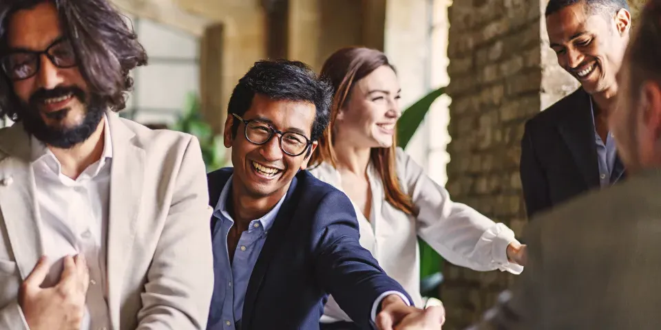 Group of diverse professionals celebrating with a handshake at a corporate event, embodying teamwork and achievement.